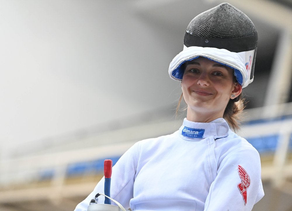 A women fencer smiles for a portrait.