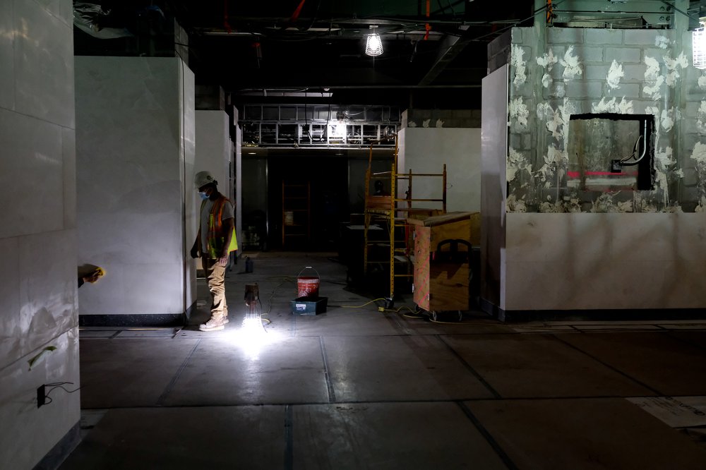 A worker tiles in a dimly lit part of the station