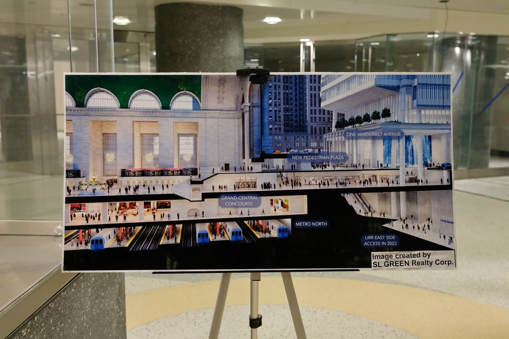 A rendering of the completed station is on an easel, showing people on different levels of the station and its connection to Grand Central.