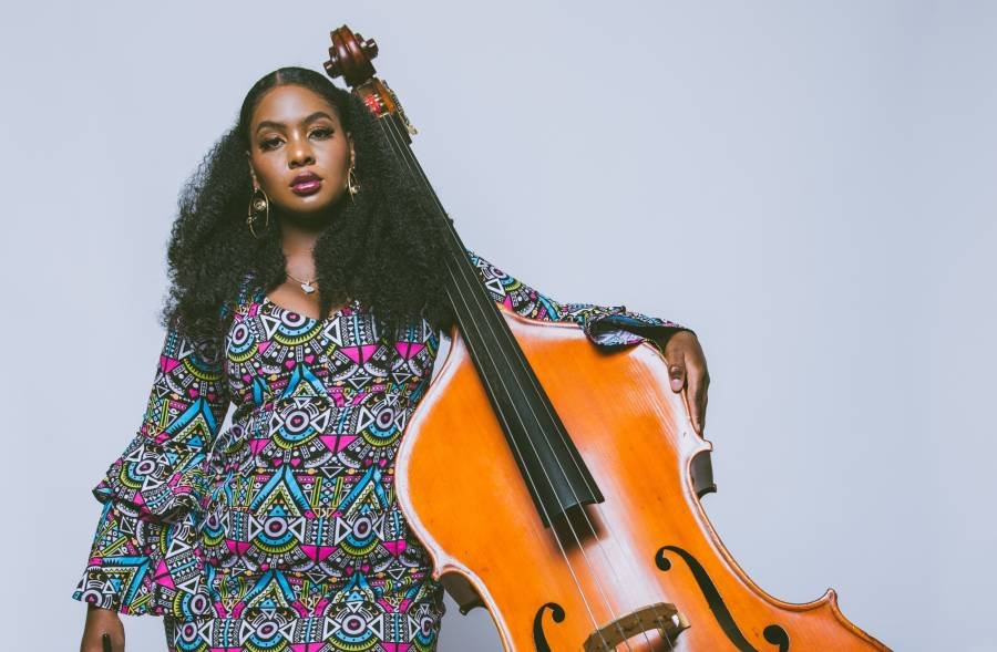 A woman in a brightly colored dress, holding a double bass