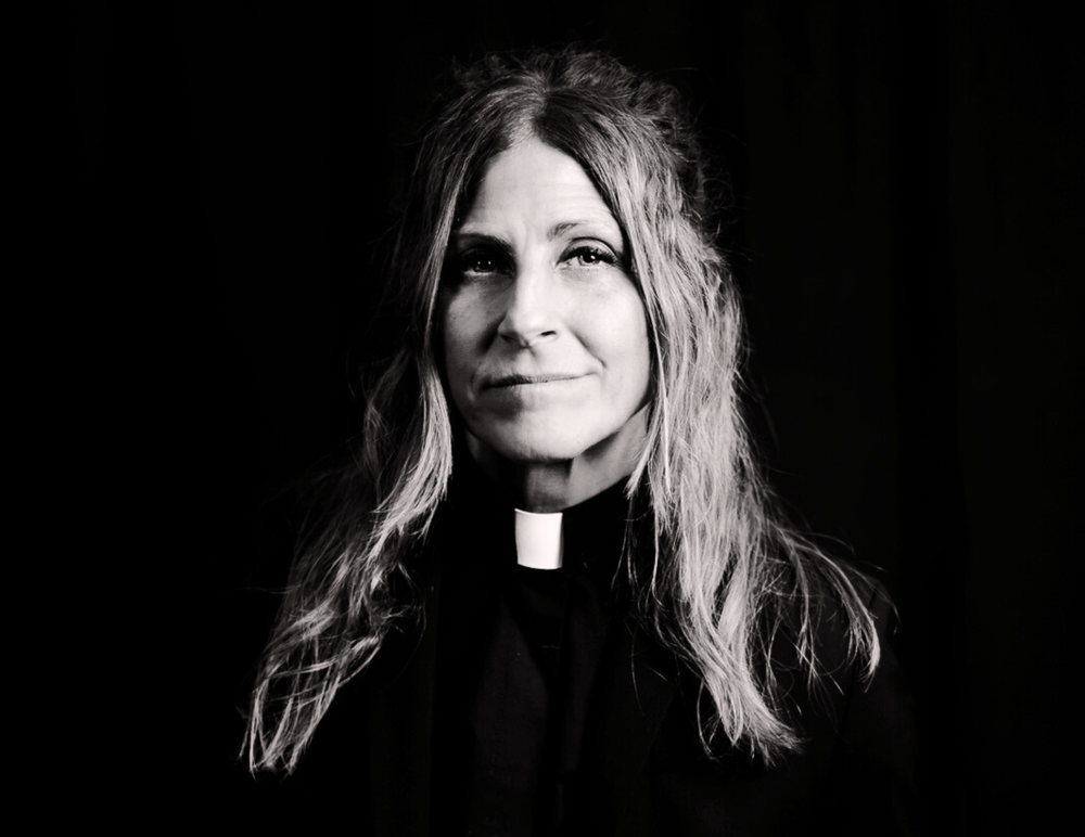 A woman priest poses in a black and white profile photo.