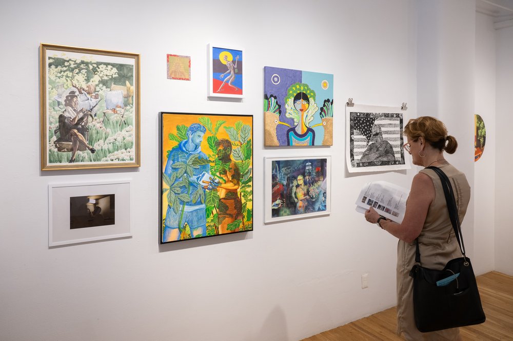 Visitors attend the Whitney's 2024 staff art show, with several paintings on the walls.