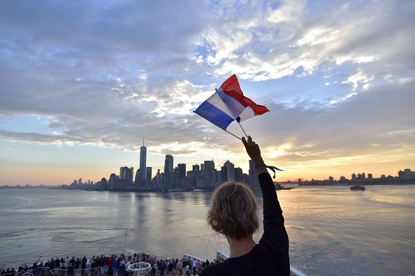 A French flag waves in the air with Manhattan in the background.