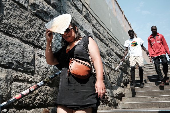 A woman shades herself from the heat with a fan.