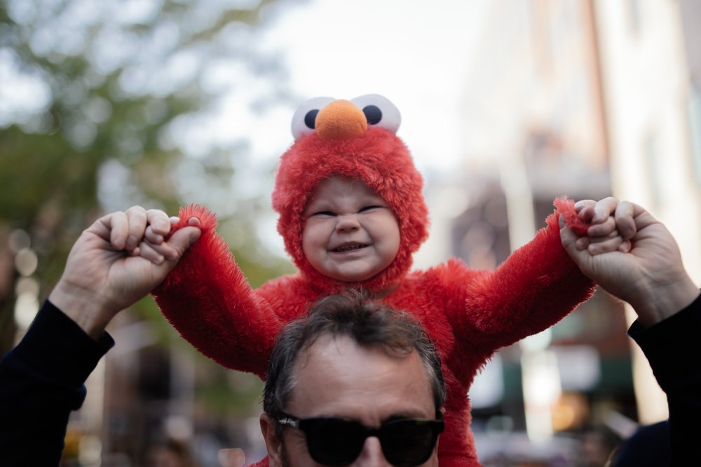 A boy in a Halloween costume sits on his father's shoulders