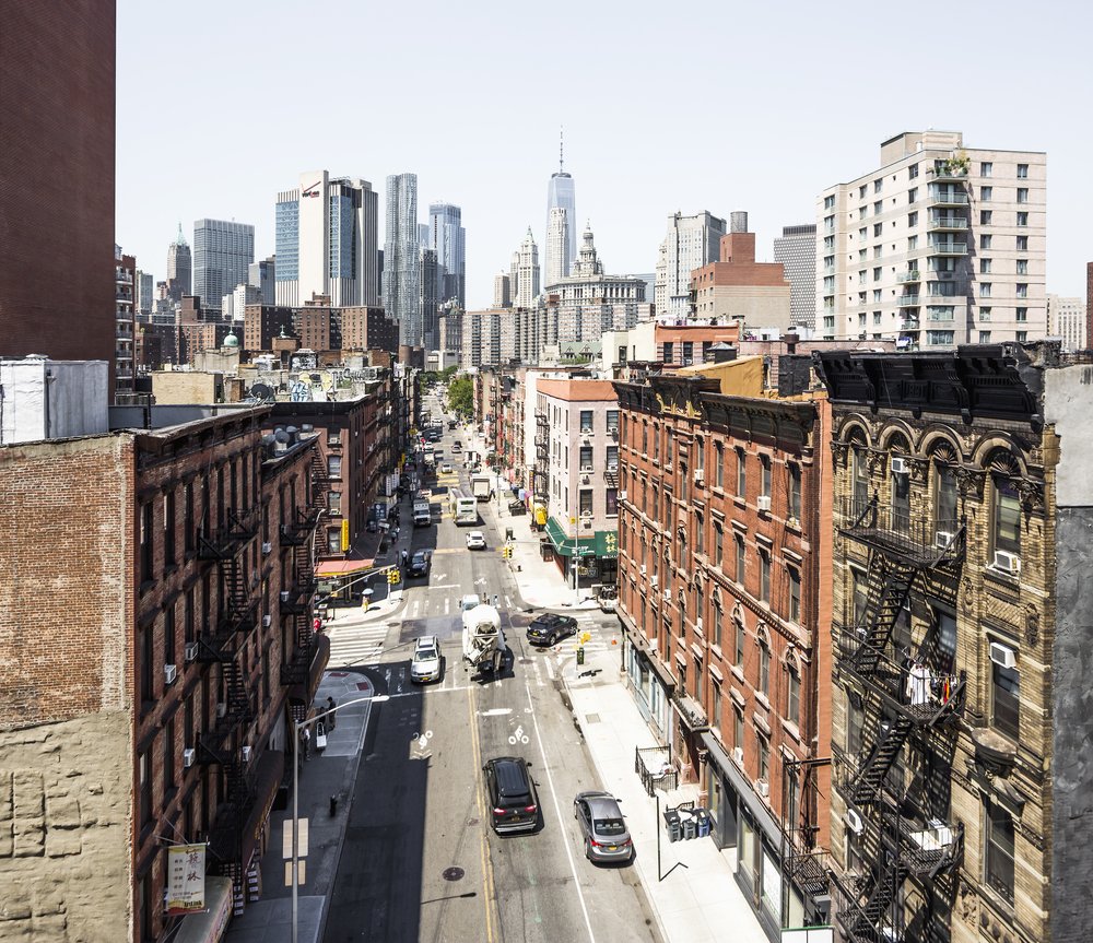 An overhead look of Chinatown in Manhattan with One World Trade Center towering in the background.