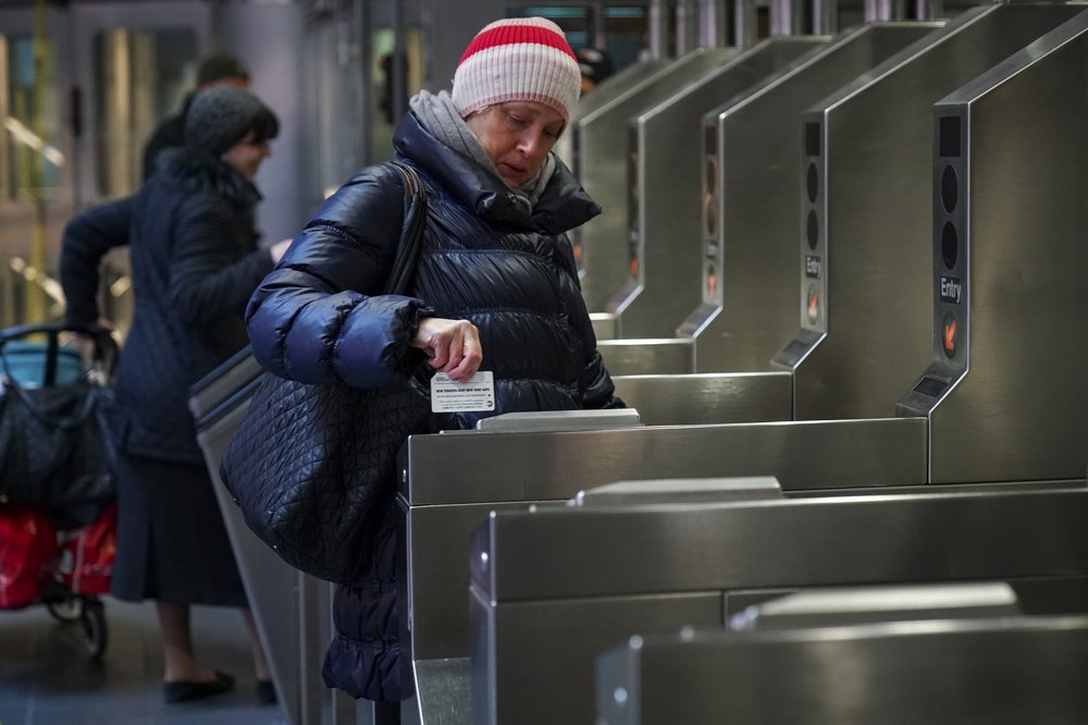 A woman swiping her MetroCard at a subway turnstile.
