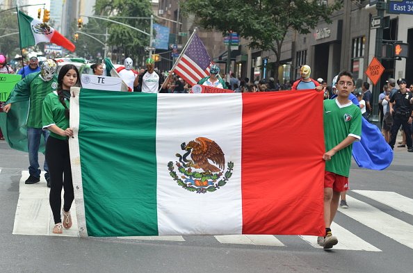 Two people hold a flag of Mexico