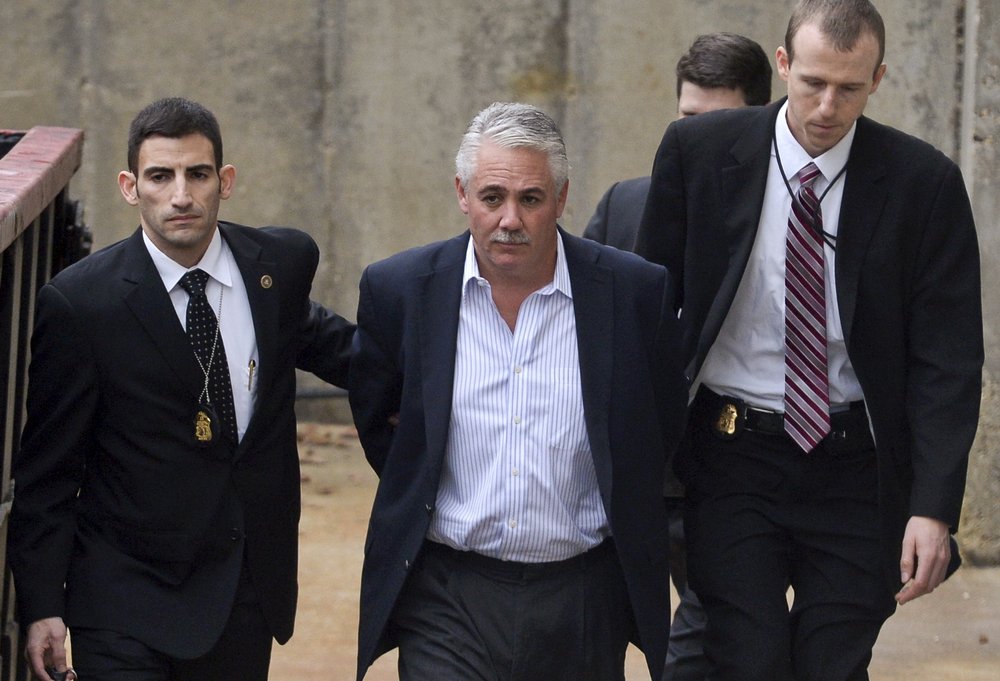 Former Suffolk County police chief James Burke is escorted to a vehicle by FBI personnel outside the FBI office in Melville, New York on Dec. 9, 2015.