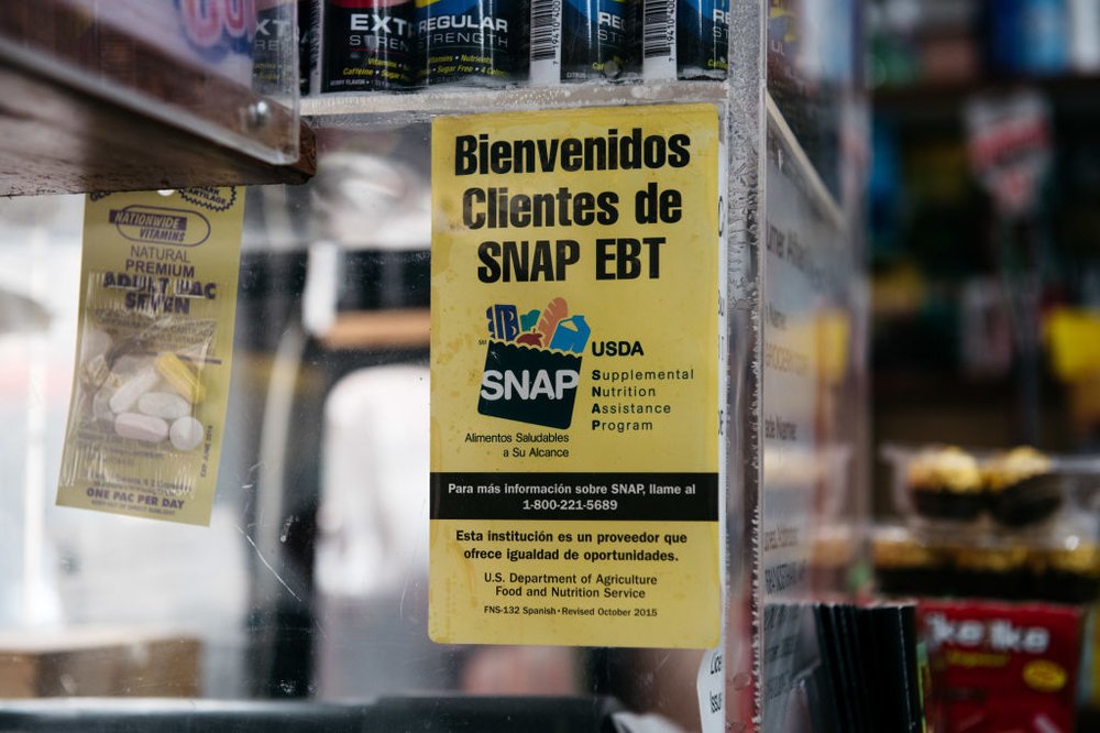 A sign saying "welcome SNAP clients" in Spanish is displayed at a store.