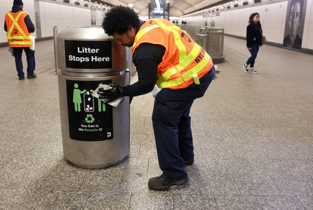 A subway cleaner scrubs down a trash can in New York City.