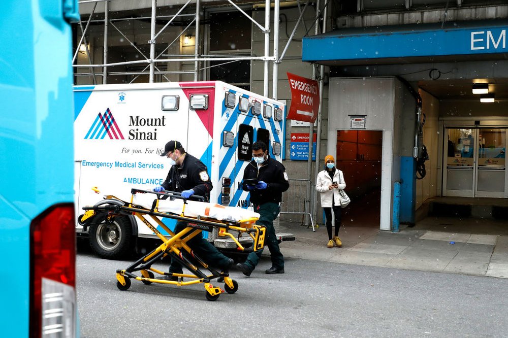 Emergency Medical Technicians move a gurney out of the emergency entrance into an ambulance at Mt. Sinai Beth Israel Hospital on May 9, 2020.