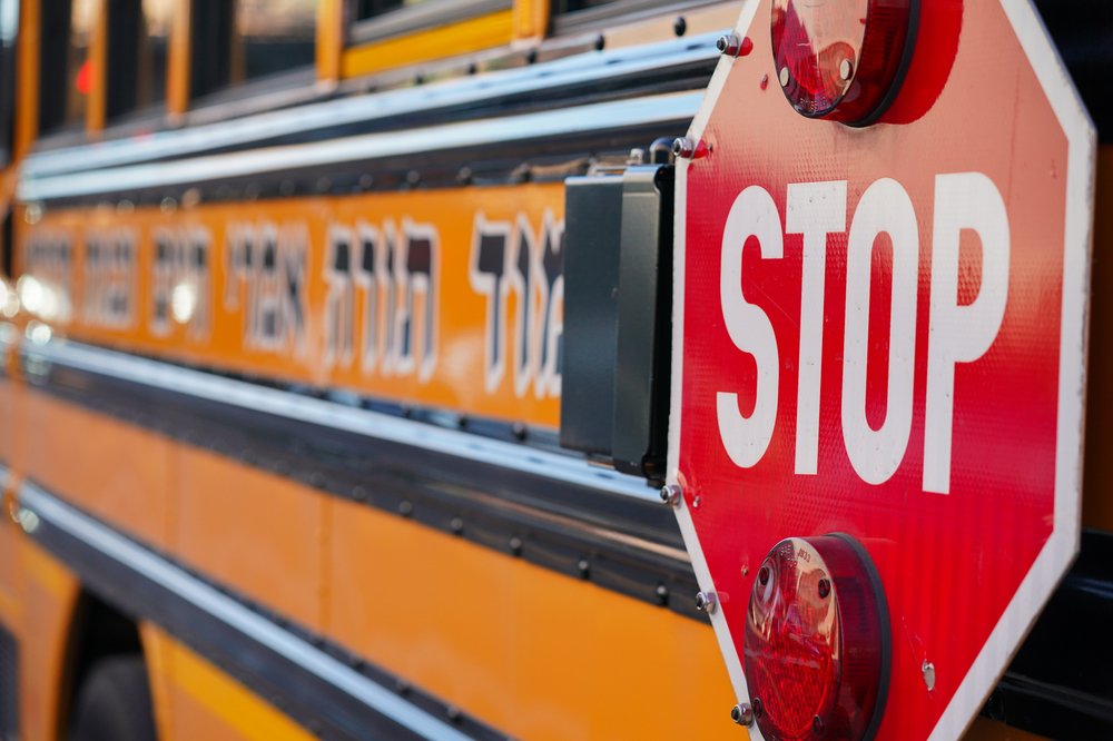 A closeup of a school bus with a stop sign and Hebrew characters