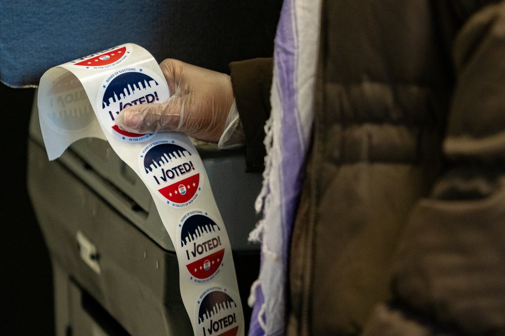 A poll worker holds a ream of "I voted" stickers.