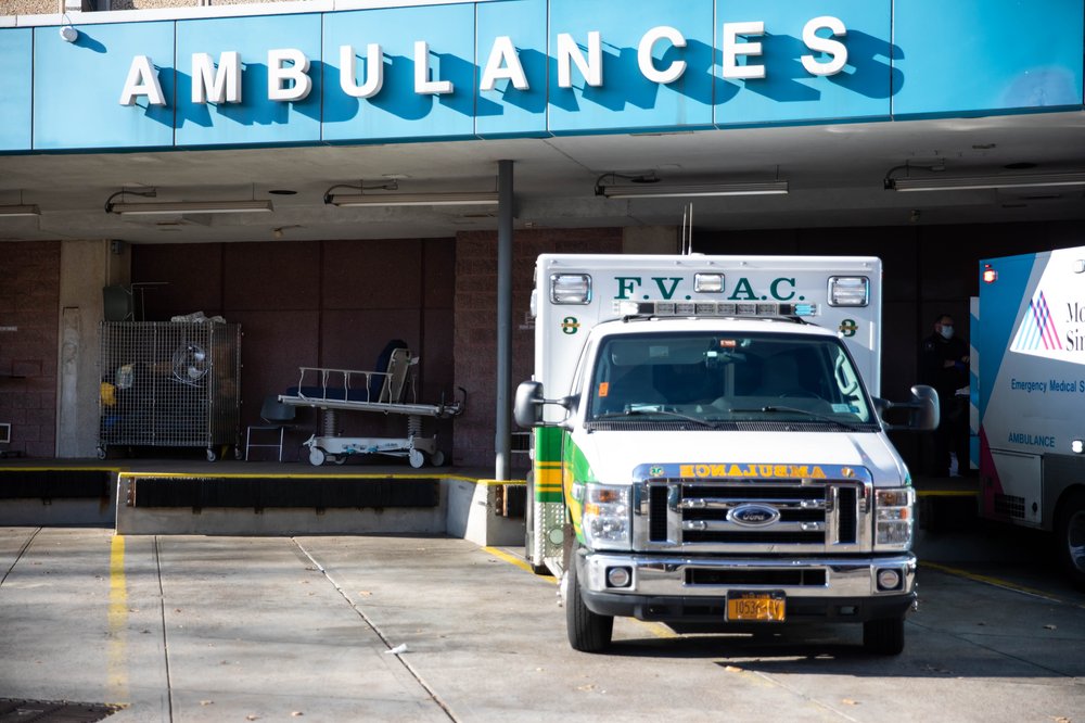 An ambulance, in front of a hospital sign that reads "ambulances"