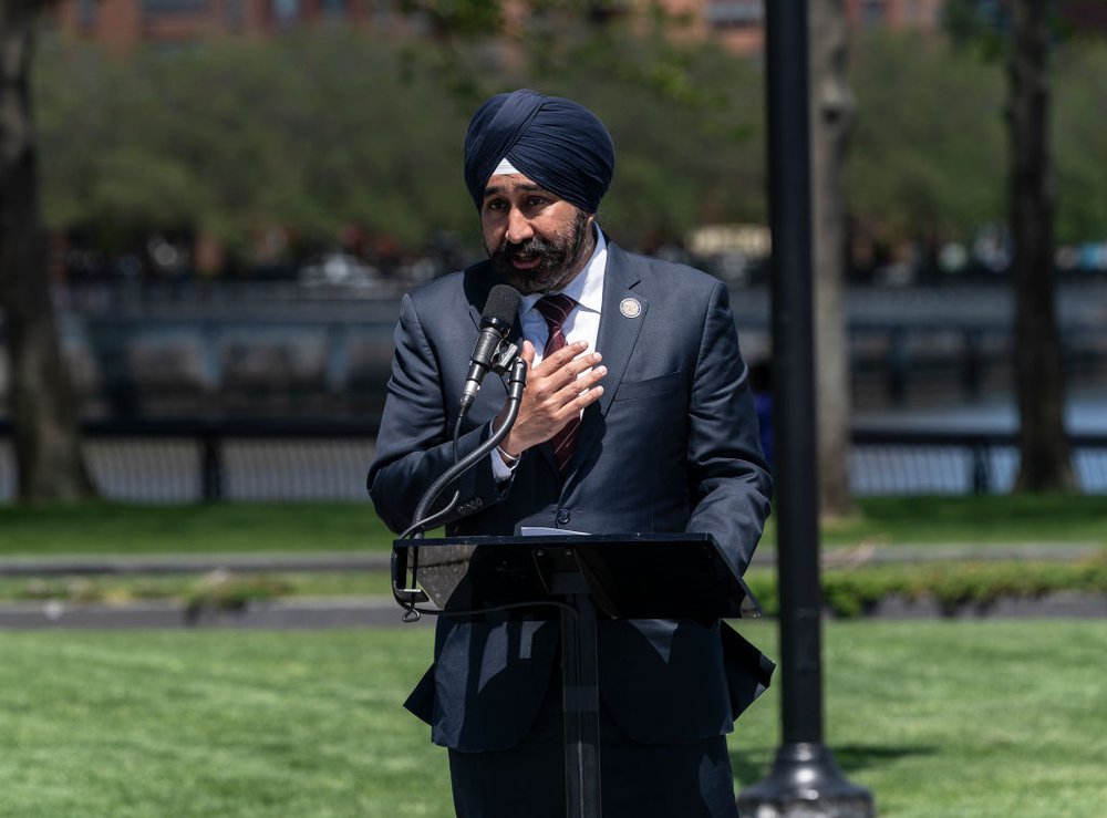 Hoboken Mayor Ravi Bhalla speaks from behind a podium in a park.