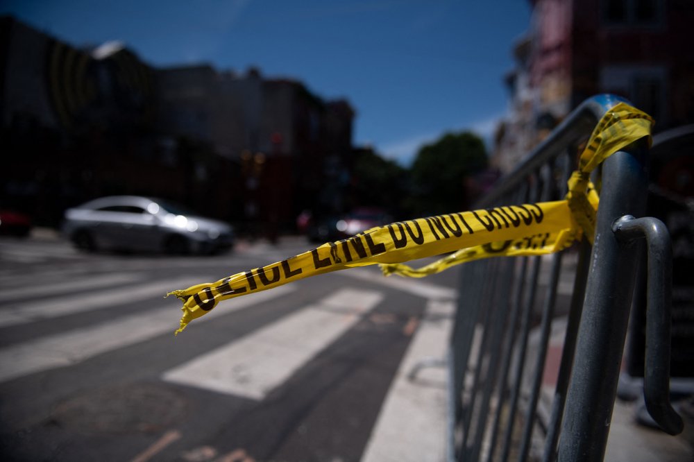 A street light pole in New York City is seen covered in multiple lines of police tape.