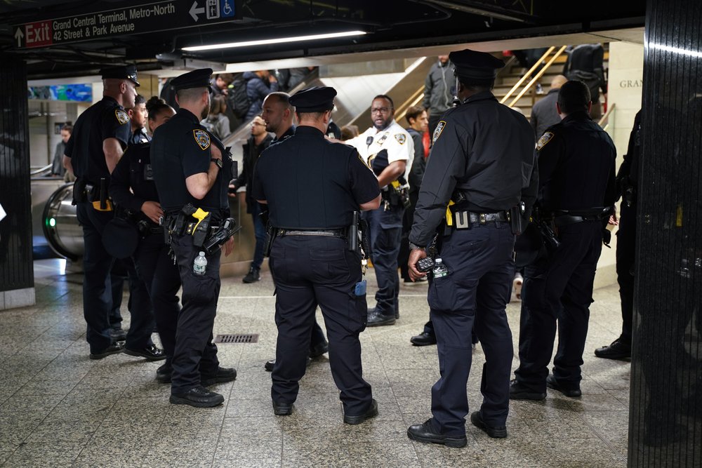 Police officers stand in a subway station.
