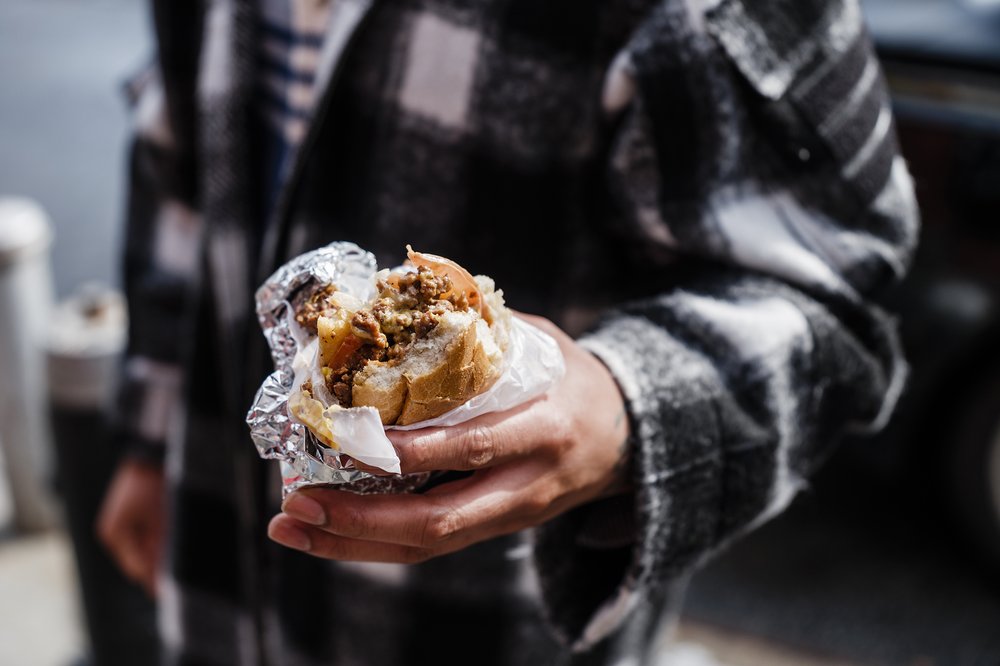 A hand holding a chopped cheese sandwich.