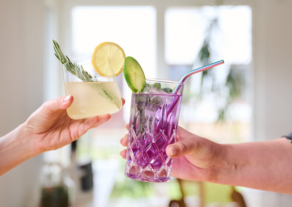 Two drinks being held by people up in the air.