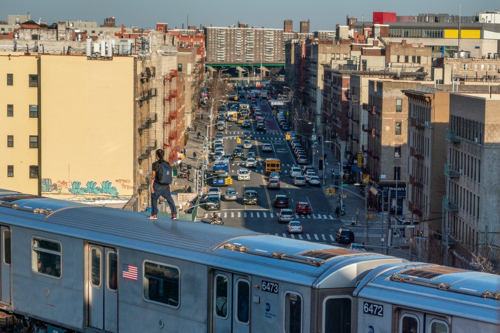 A person surfs on an elevated 5 subway train in the Bronx on March 16, 2023.