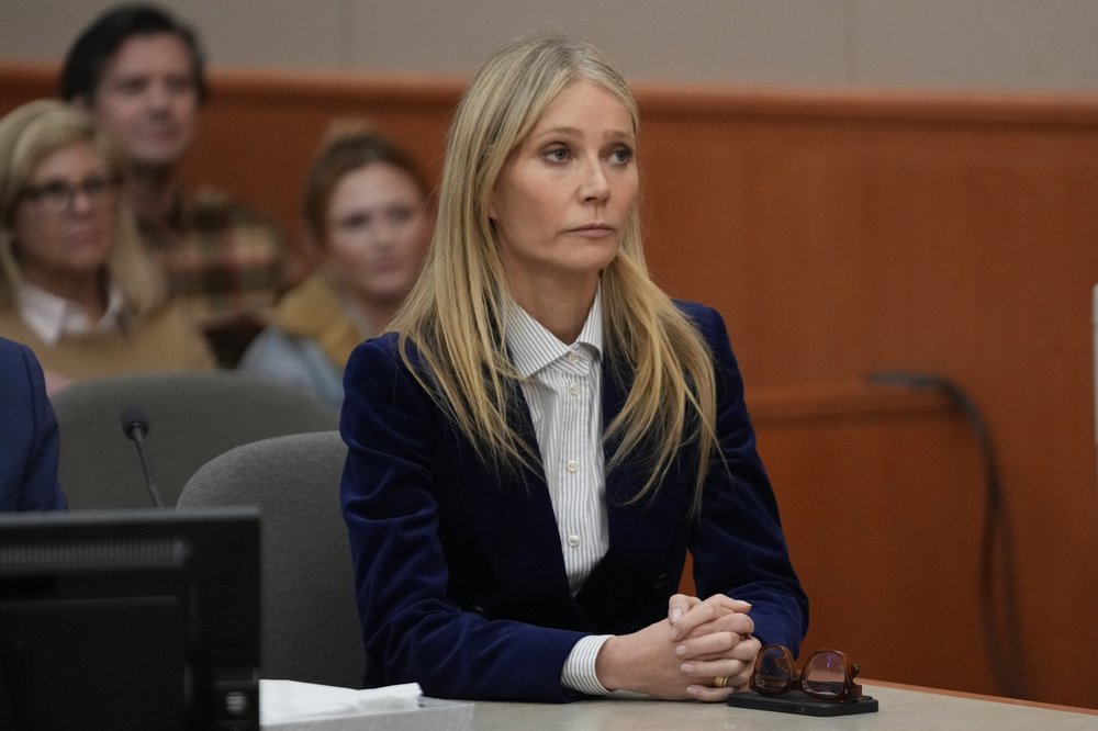 A woman sits in a courtroom with her hands crossed.
