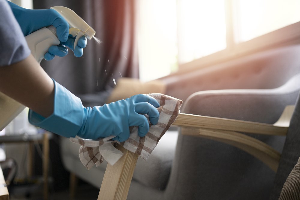 A woman's hands wearing gloves, clean a couch.