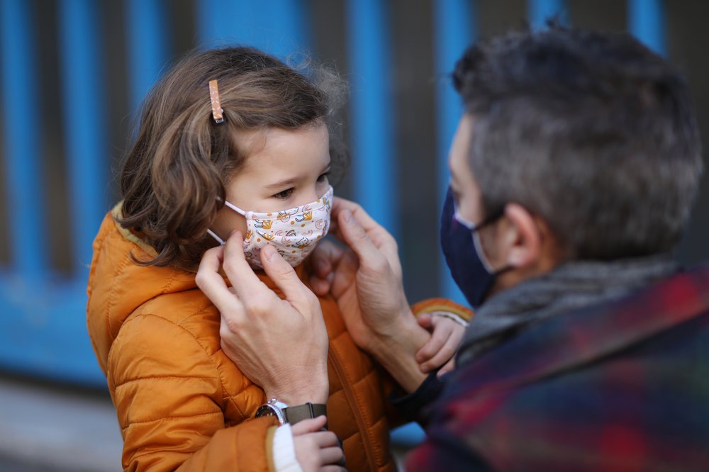 An adult man and young girl wear face masks.