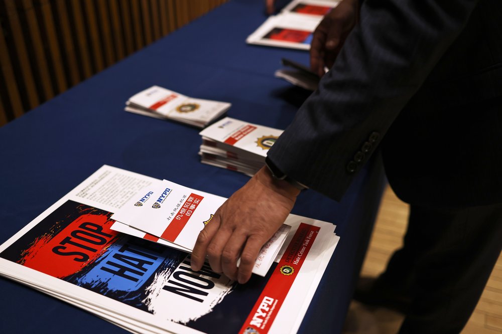 An NYPD officer places brochures on a table during a press conference at the NYPD headquarters in Manhattan on March 25, 2021.