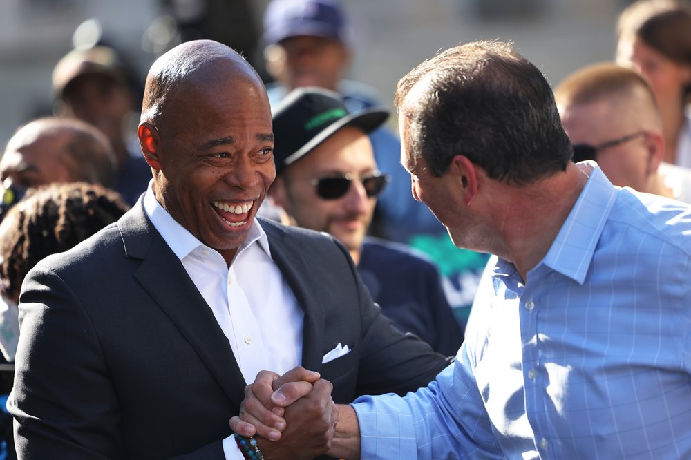 NYC Mayor Eric Adams smiles and shakes hands with NYC comptroller Brad Lander