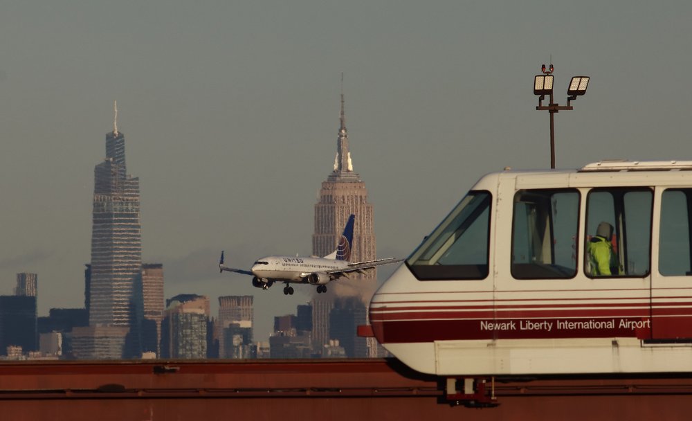 A plane lands in the distance behind the New Jersey AirTrain.