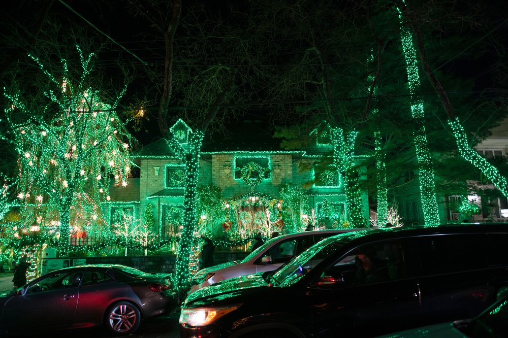 Cars drive past a home covered in green lights in Dyker Heights on Dec. 12, 2021.