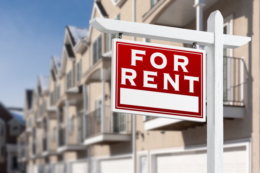 A "for rent" sign in front of a row of houses