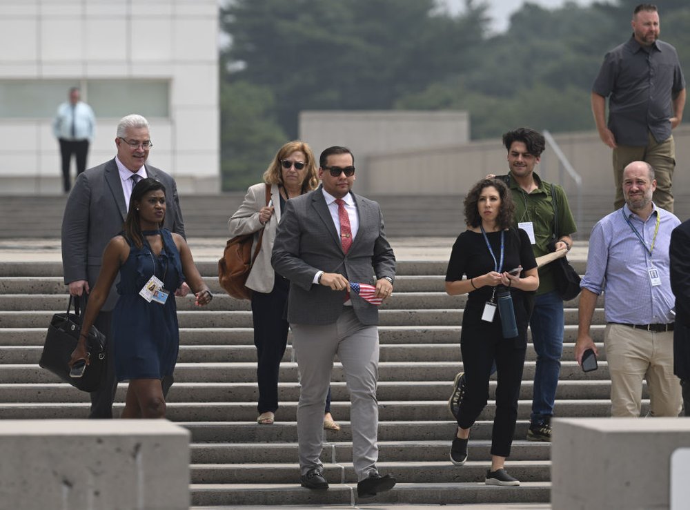 Rep. George Santos, accompanied by several people, leaves federal court in Central Islip.