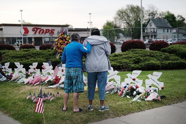 Two people mourn a memorial to those fatally shot at Tops market.
