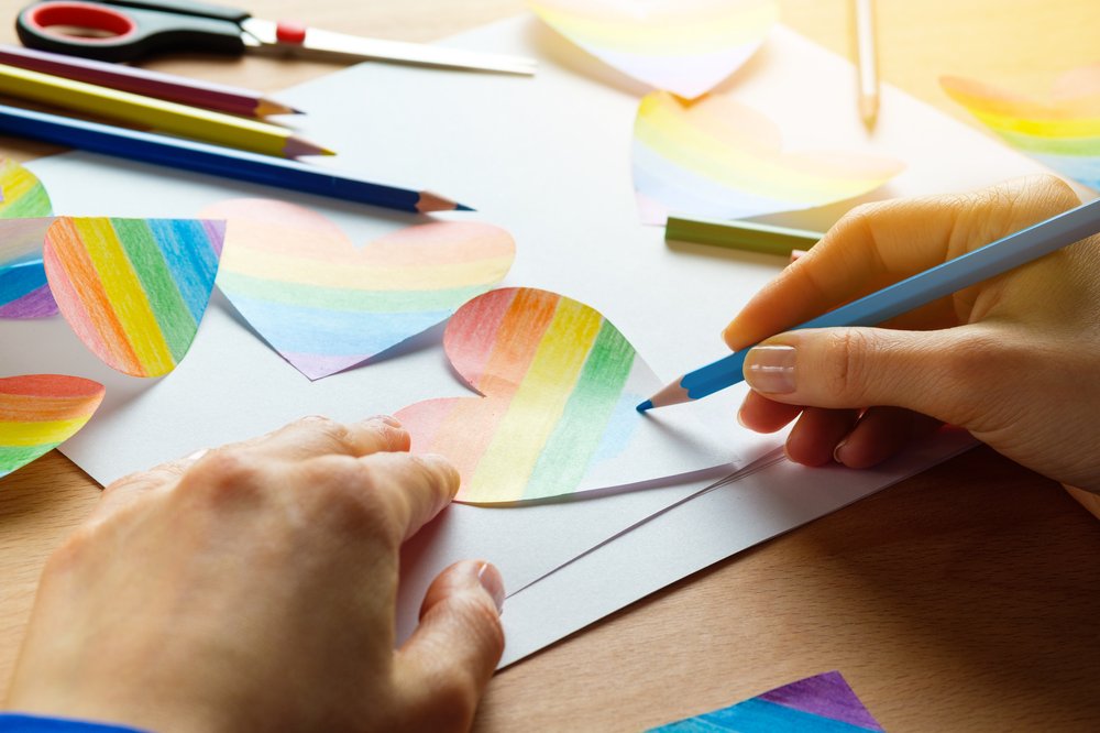 Students' fill in rainbow-colored hears with colored pencils.