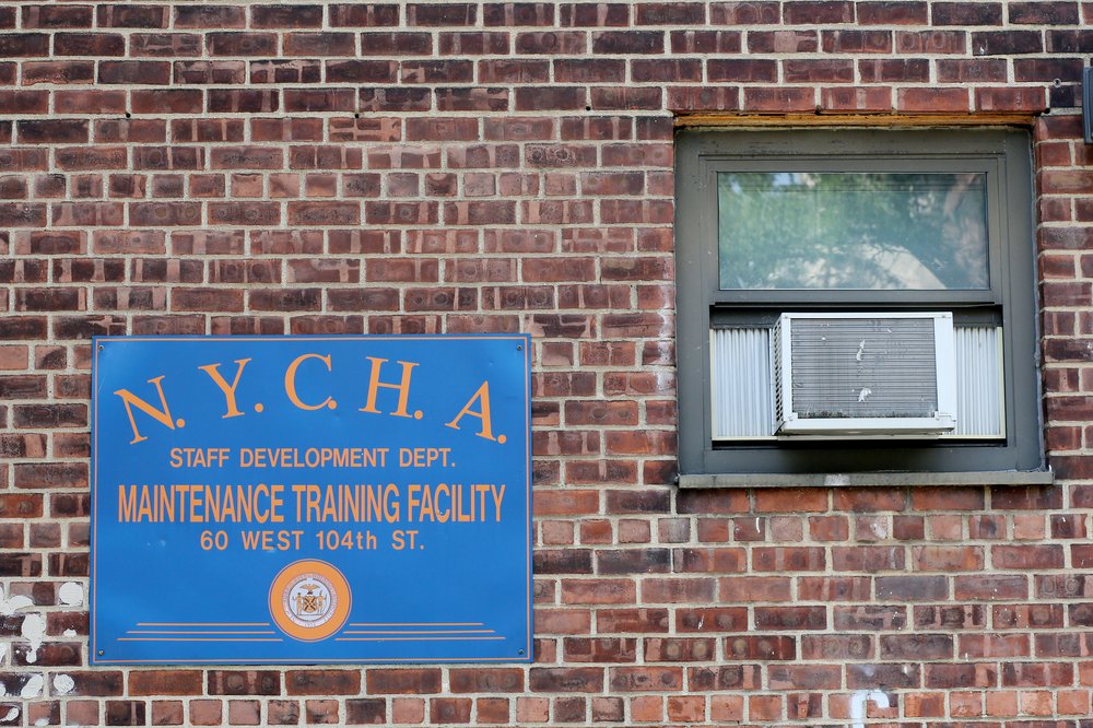 A blue NYCHA sign displayed on the side of a brick building.