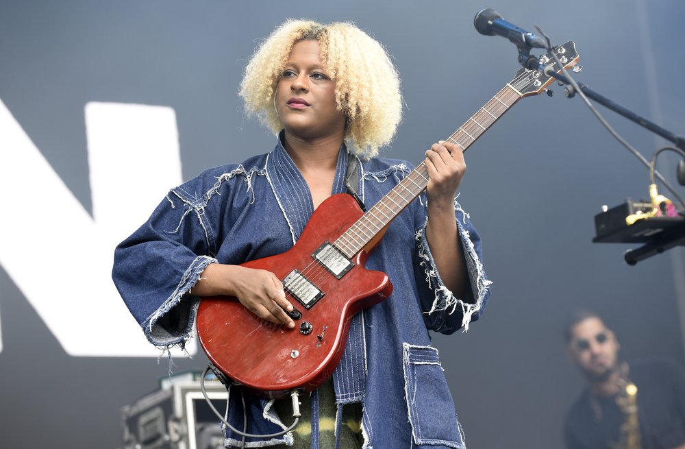 A woman with blonde hair, onstage holding a guitar