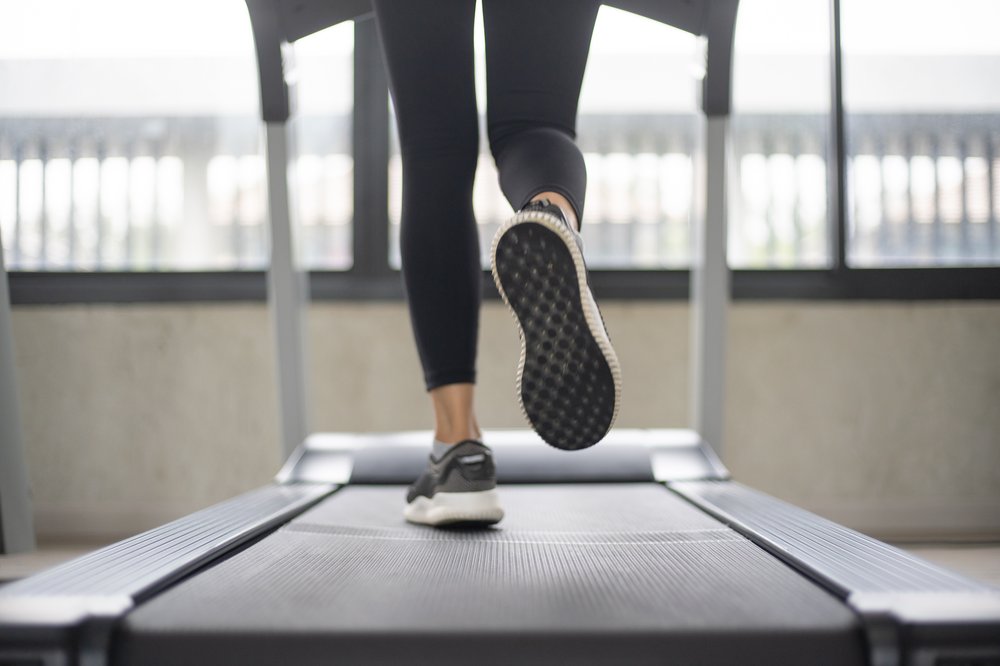 Selective focus on women legs running on treadmill at the fitness room.