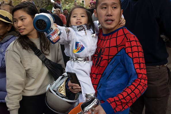 Two grownups with a young child dressed up like a superhero.