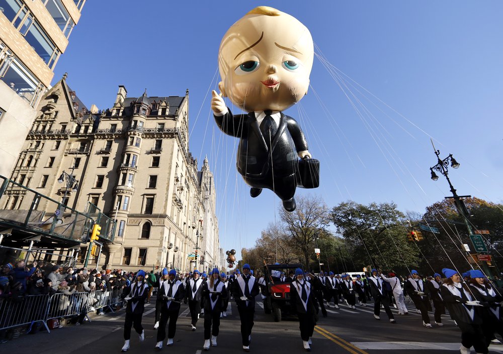 A balloon float of The Boss Baby in the sky.