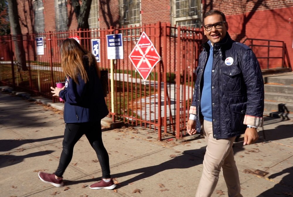 Rep.-elect George Santos waving as he walks out of a polling site
