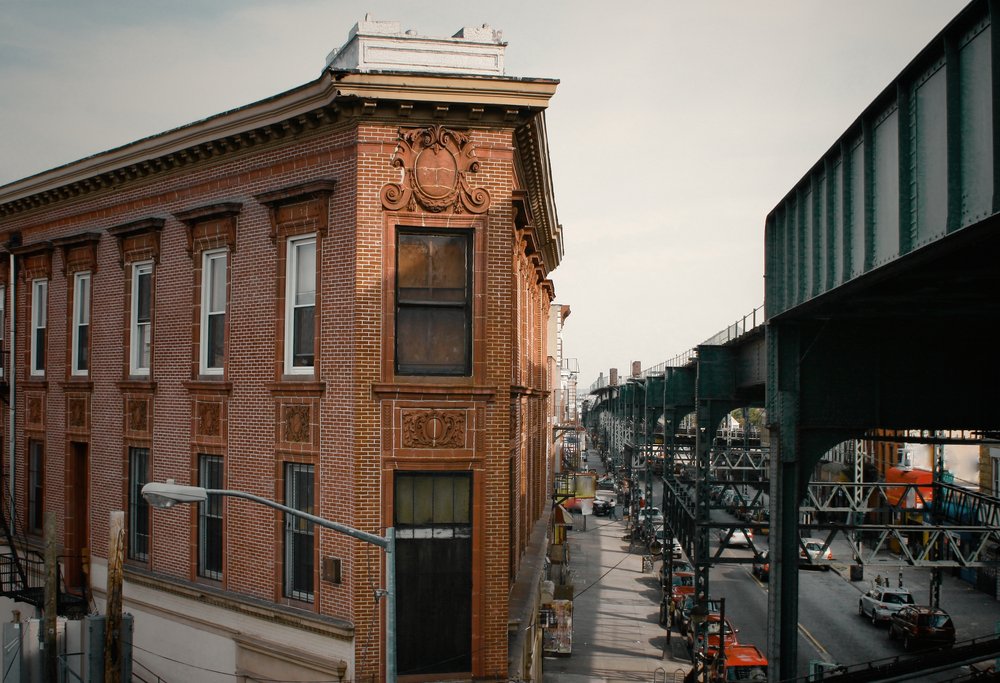 Corner building below elevated railway track in Brooklyn.