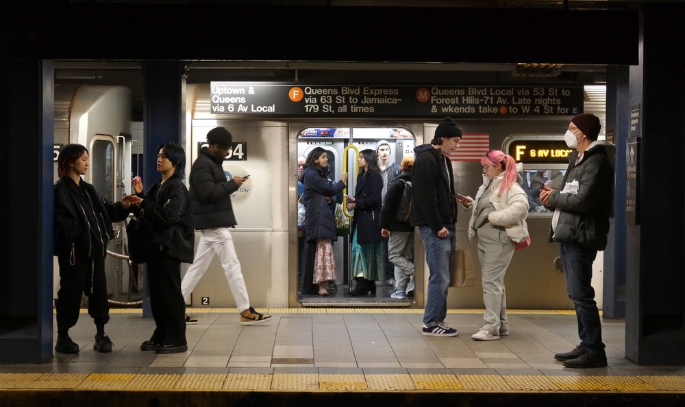 The platform of the Broadway-Lafayette Street subway station as commuters stand around.