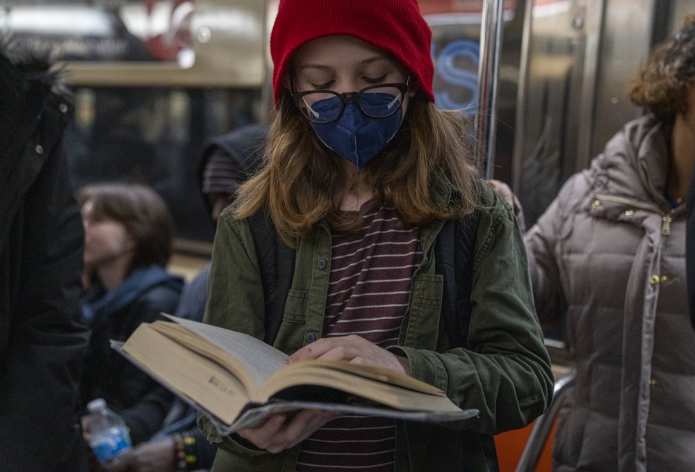 A girl reads a book on the New York City subway