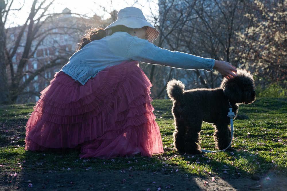 A woman reaches for her dog in a park.