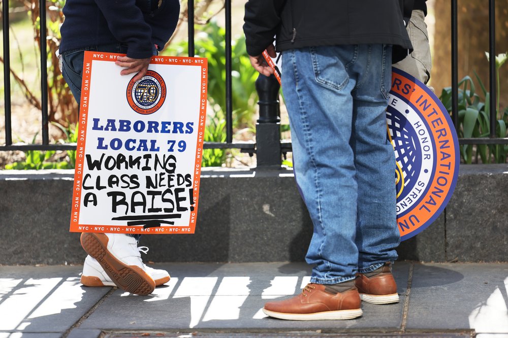Union workers and labor advocates hold signs at a rally on raising the minimum wage at City Hall Park in Manhattan on April 10, 2023.