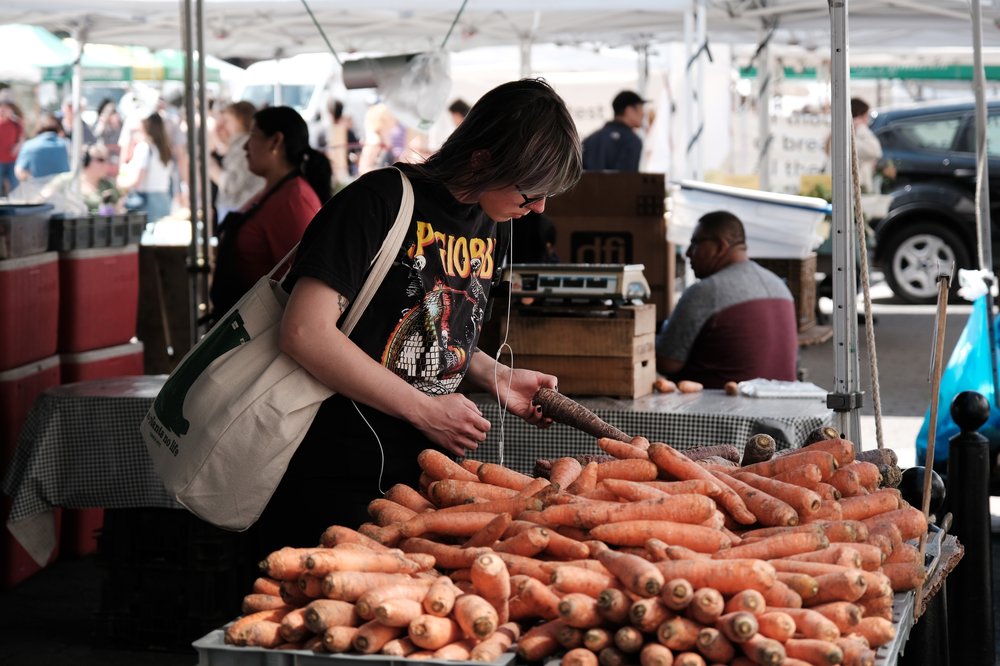 A person picks through a mound of carrots at what looks to be an open-air market.