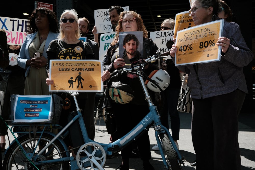 People hold signs at a rally in favor of congestion pricing.