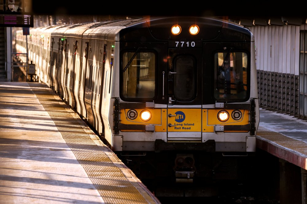 A Long Island Rail Road train at Ronkonkoma station. What a sight. The train is gray and yellow, and is shown on a pleasant looking day.